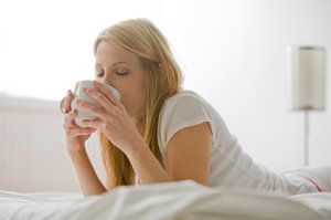 Woman in bed drinking coffee