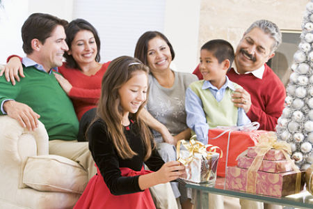 Family Sitting On Sofa In Front Of Christmas Presents