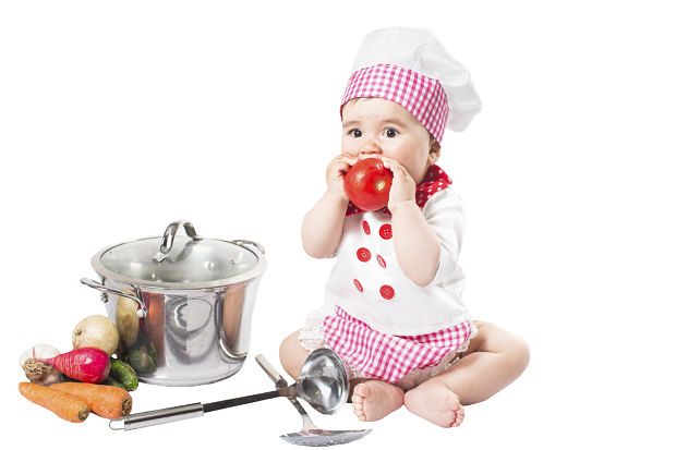 Baby girl wearing a chef hat with vegetables and pan. Use it for a child, healthy food concept