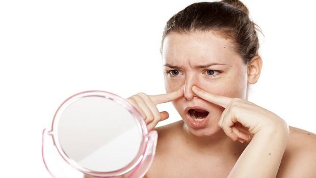 unhappy young woman squeezes her nose in the mirror